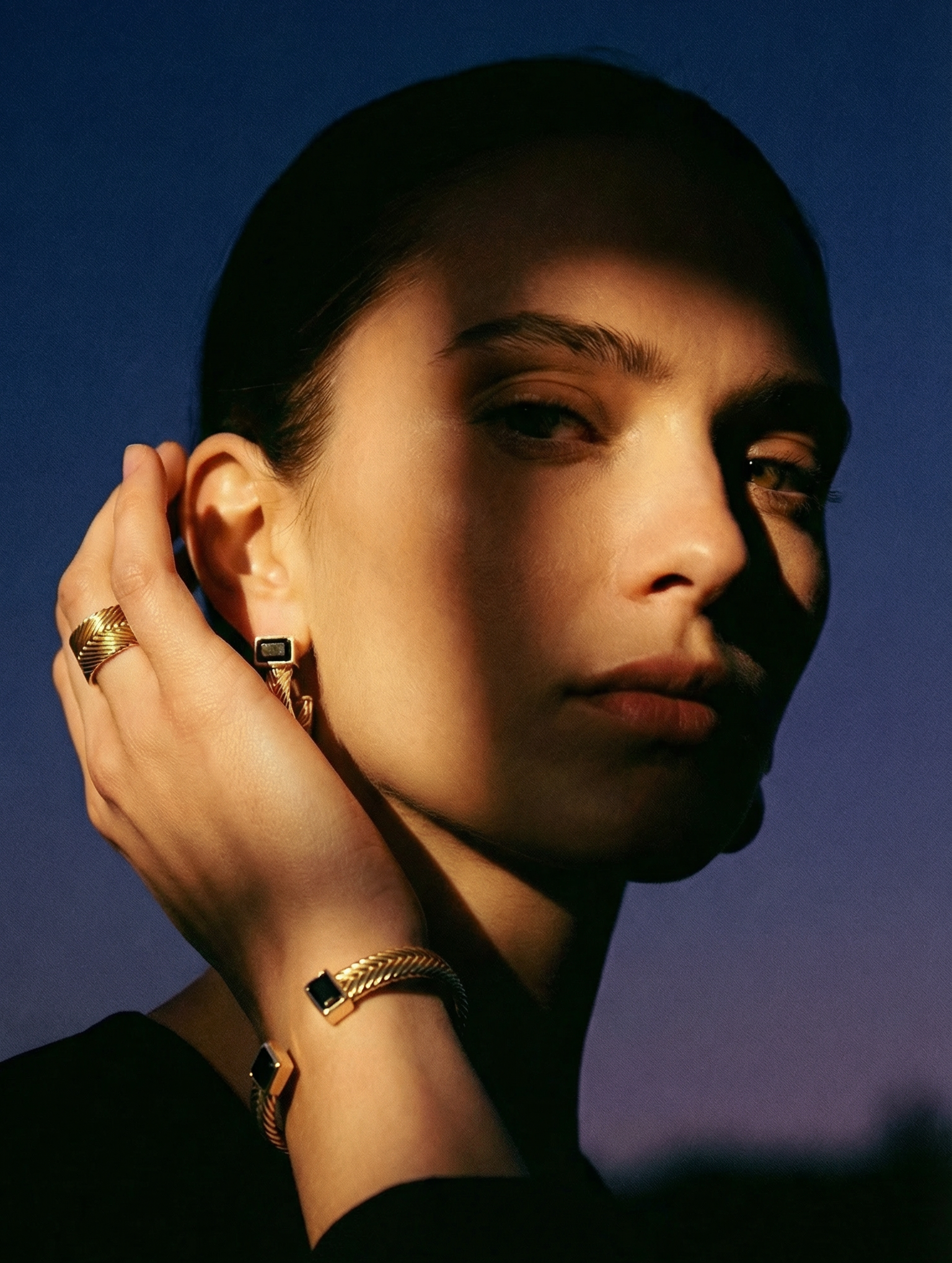 Model wearing Aphrodite cuff bracelet in gold vermeil on wrist, showing handwoven texture and black spinel stone details
