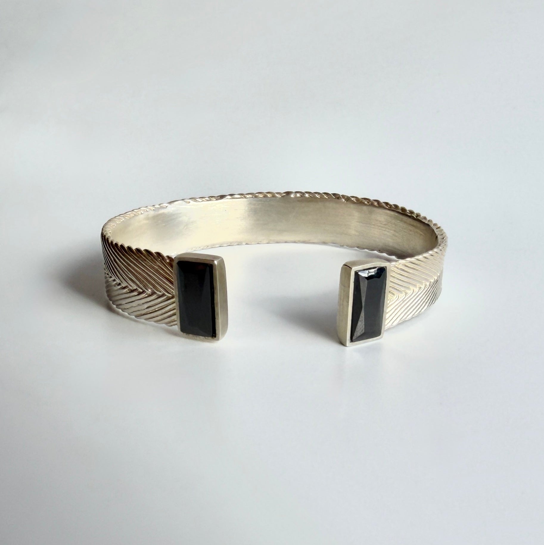 Aphrodite cuff bracelet in Sterling silverwith handwoven texture and two rectangular black spinel stones at open ends