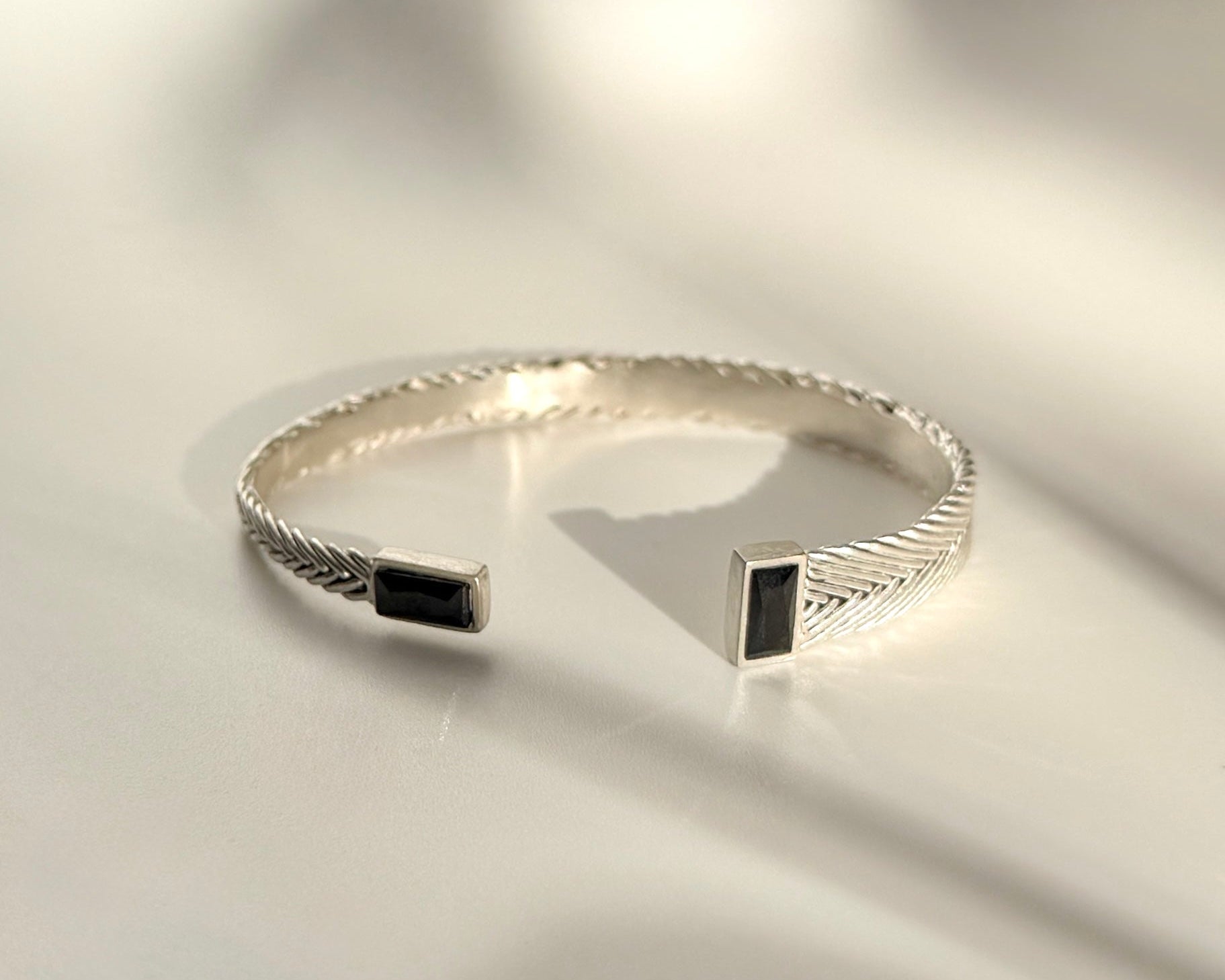 Hestia Cuff in sterling silver with handwoven detail, black spinel stones, and asymmetrical sculptural form