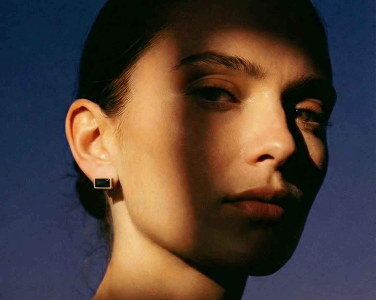 Model wearing Spinel Post Earring in gold vermeil, showcasing minimalist black spinel stud design