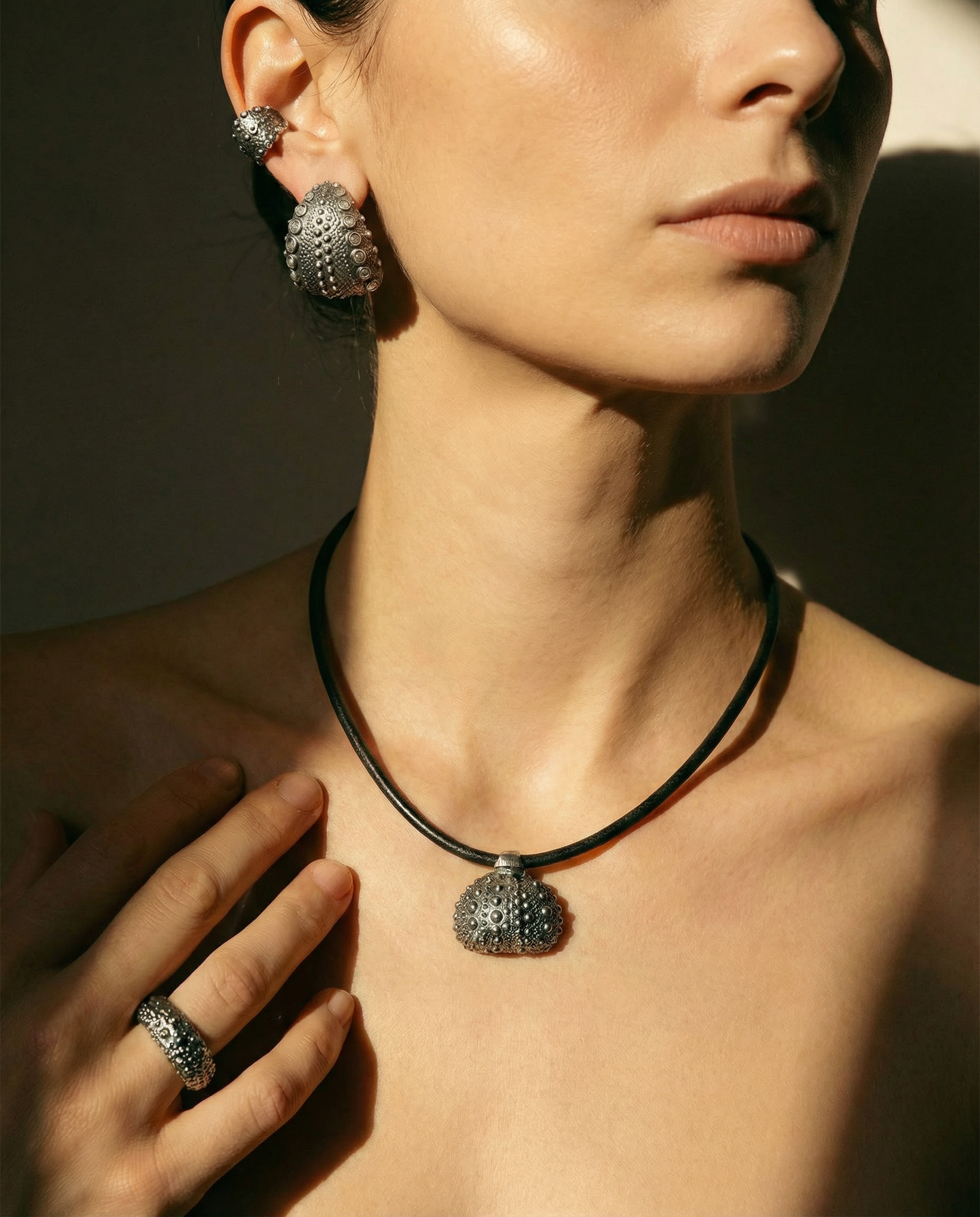 Model wearing Urchin Hoop Earrings, necklace, and ear cuff in oxidized sterling silver with diamonds, showcasing preserved sea urchin shell texture and timeless hoop design