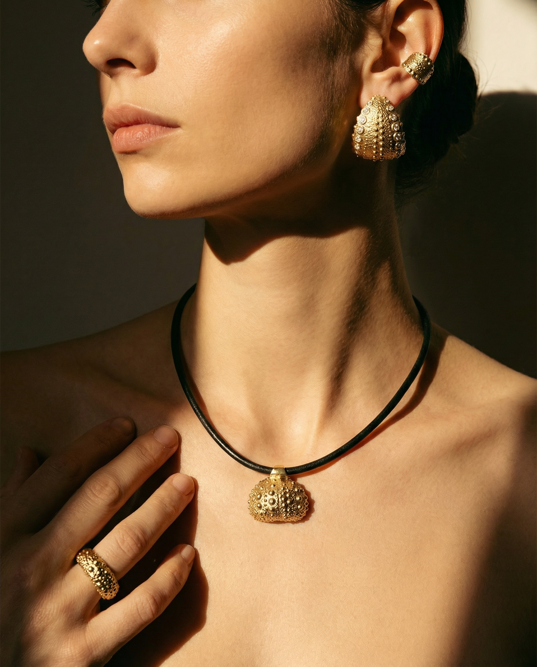 Model wearing Urchin Hoop Earrings, necklace, ear cuff, and ring in gold vermeil with diamonds, showcasing preserved sea urchin shell texture and timeless hoop design
