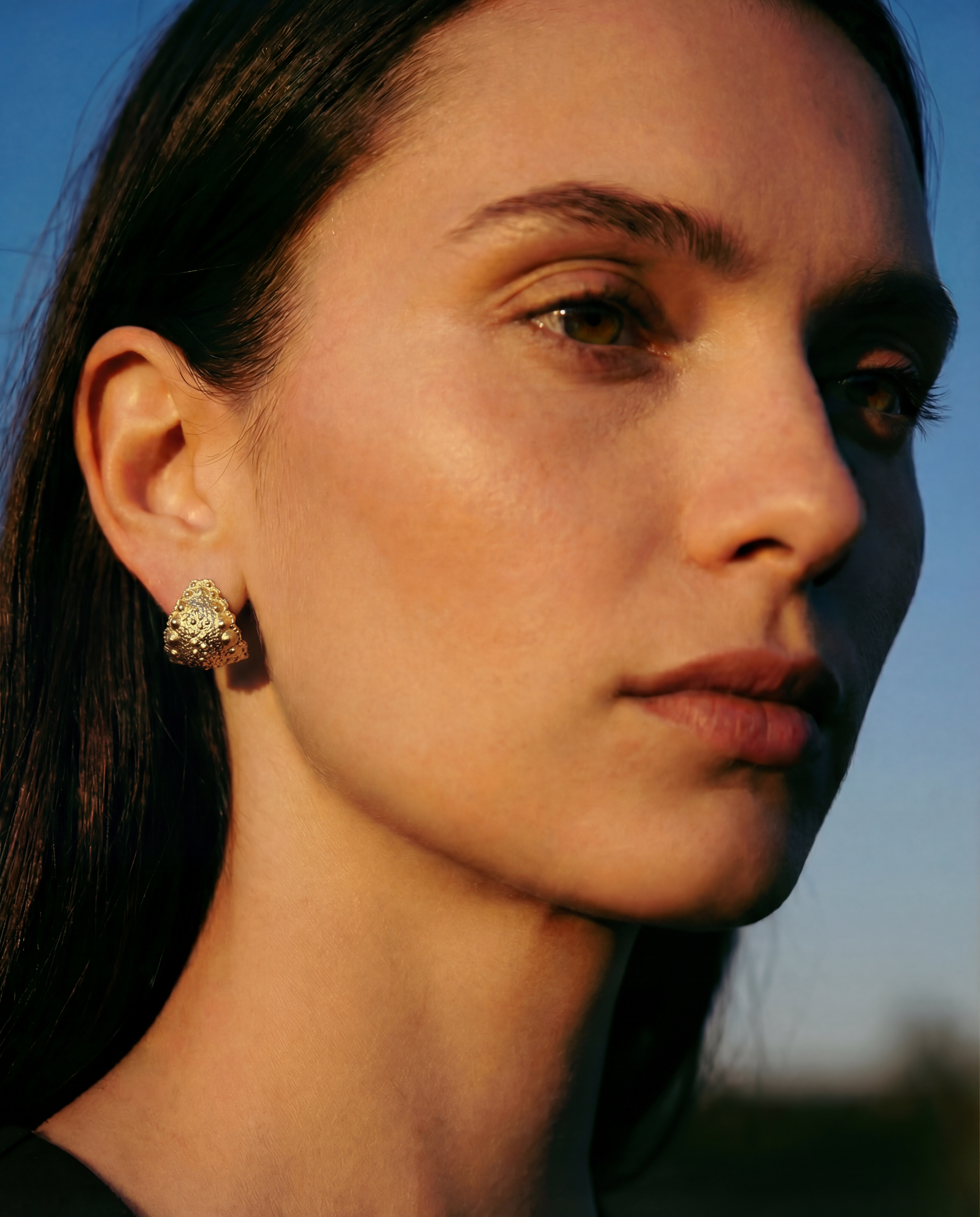 Model wearing Urchin Hug Earrings in gold vermeil, showcasing preserved sea urchin shell texture and sculptural hoop design